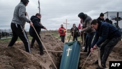 Relatives of Mykhailo Romaniuk, 58, who was shot dead on his bicycle on March 6, help to bury his coffin at a cemetery in Bucha, Apr. 19, 2022.