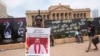 Seorang pengunjuk rasa memegang plakat bergambar PM Mahinda Rajapaksa di dekat kantor presiden di Kolombo, Sri Lanka, 13 April 2022. Poster itu berbunyi "Jatuhkan pemerintah, Ubah sistem." (AP/Eranga Jayawardena)