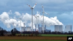 FILE - Renewable and fossil-fuel energy is produced by wind generators, seen in front of a coal-fired power plant near Jackerath, Germany, Dec. 7, 2018. 
