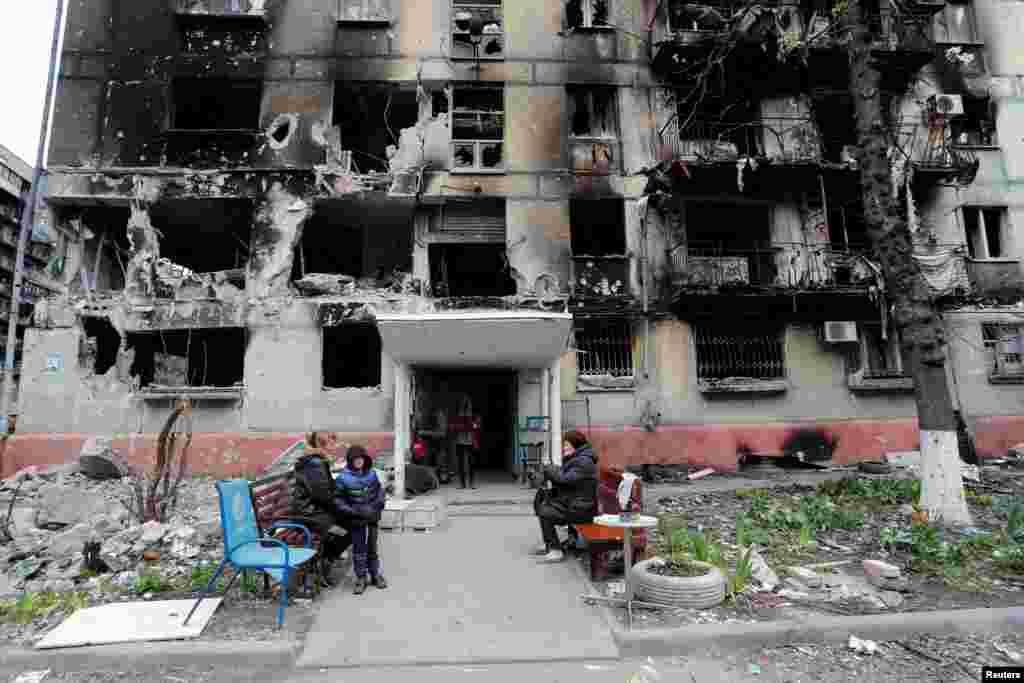 Local residents gather outside a residential building heavily damaged during Russia&#39;s invasion of Ukraine, in the southern port city of Mariupol. (REUTERS/Alexander Ermochenko)