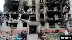 ساکنان ماریوپول در کنار یک ساختمان تخریب‌شده توسط روسیه. ٢١ آوریل ٢٠٢٢
