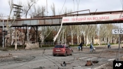 Residentes pasan frente a una parte destruida de la planta metalúrgica Illich Iron & Steel Works, la segunda empresa metalúrgica más grande de Ucrania, en Mariupol, el 16 de abril de 2022.