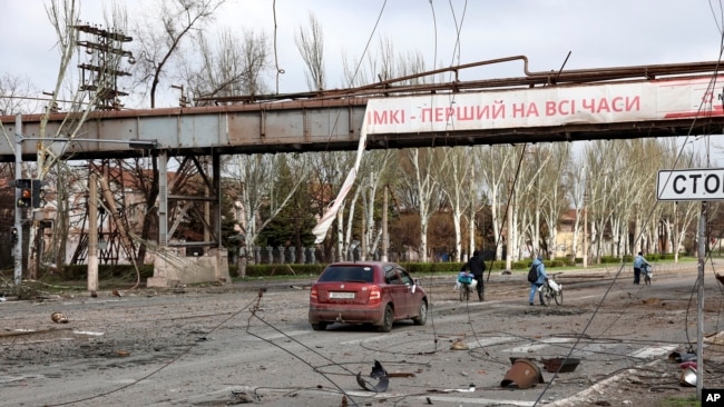 Residentes pasan frente a una parte destruida de la planta metalúrgica Illich Iron & Steel Works, la segunda empresa metalúrgica más grande de Ucrania, en Mariupol, el 16 de abril de 2022.