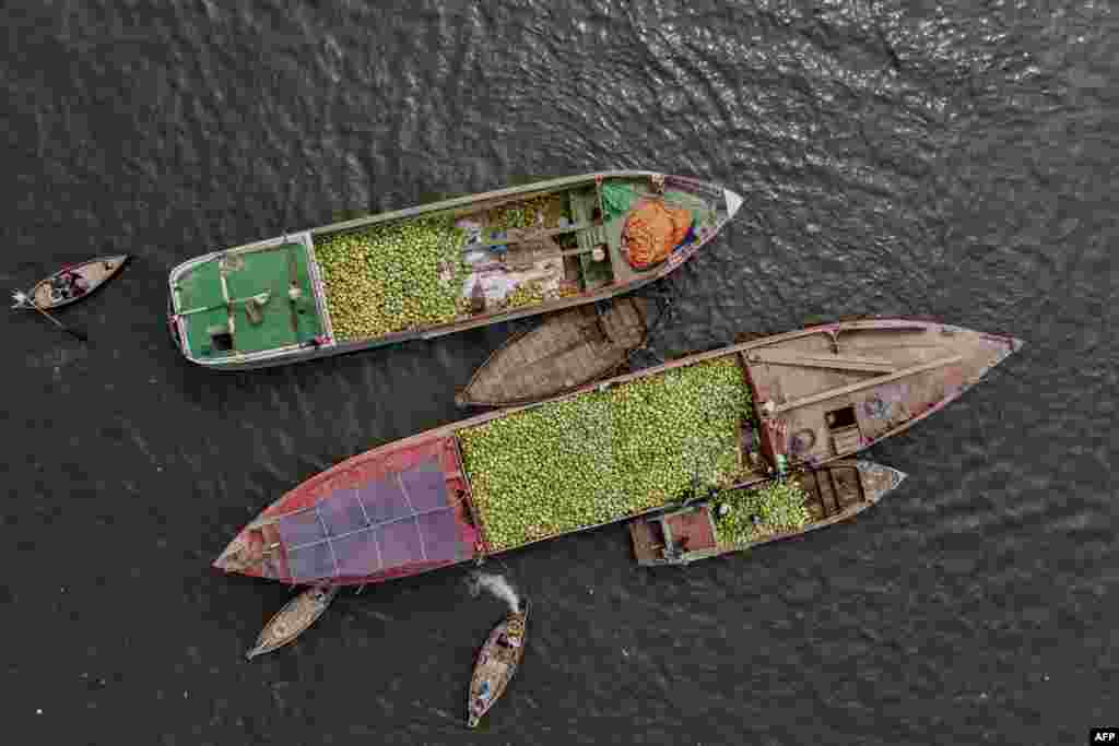 This aerial photo shows workers unloading watermelons from a cargo vessel onto a smaller boat on the Buriganga River in Dhaka, Bangladesh.