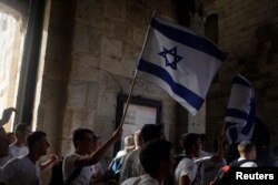 Para pemuda membawa bendera Israel dalam pawai menandai Hari Yerusalem, di tengah ketegangan Israel-Palestina, saat masuk melalui Gerbang Jaffa di Kota Tua Yerusalem, 10 Mei 2021. (REUTERS/Nir Elias)