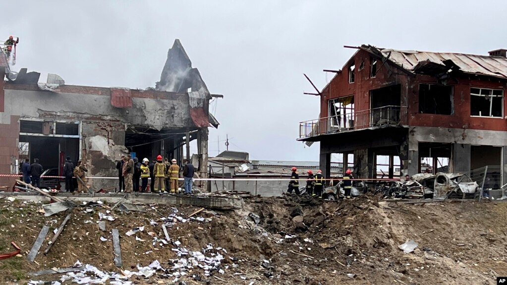 Emergency workers clear up debris after an airstrike hit a tire shop in the western city of Lviv, Ukraine, Monday April 18, 2022. (AP Photo/Philip Crowther)