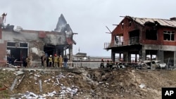 Emergency workers clear up debris after an airstrike hit a tire shop in the western city of Lviv, Ukraine, Monday April 18, 2022. (AP Photo/Philip Crowther)