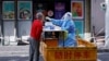 2022年4月22日，一名医护工作人员在上海街头为居民进行核酸检测。