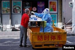 Seorang petugas medis mengenakan APD melakukan tes swab dari seorang penduduk, di tengah wabah COVID-19 di Shanghai, China 22 April 2022. (cnsphoto via REUTERS)