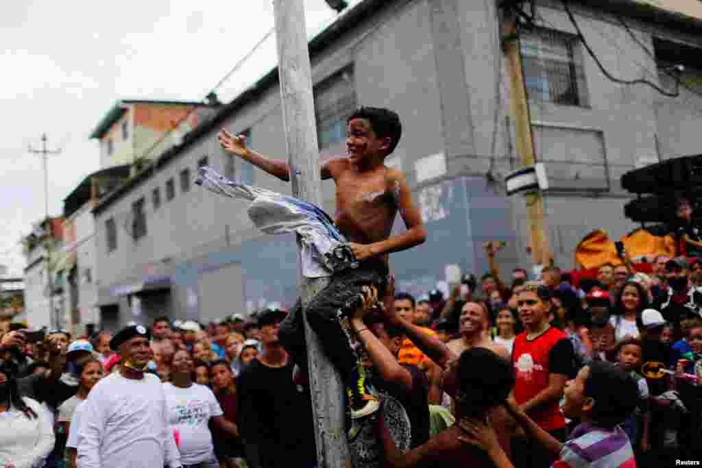 Children take part in a greasy pole game during the traditional burning of Judas, as part of the Holy Week celebrations in Caracas, Venezuela, April 17, 2022.