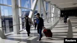 Viajeros aéreos con mascarillas protectoras, en medio de la pandemia de la enfermedad por coronavirus (COVID-19), caminan en la Terminal 5 de JetBlue en el aeropuerto internacional JFK en Nueva York, EEUU, el 16 de noviembre de 2021.