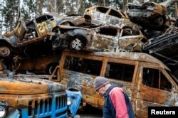 A person walks in front of destroyed cars, as Russia's invasion of Ukraine continues, in Irpin, near Kyiv, Ukraine, April 19, 2022.