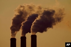 FILE - Emissions rise from the smokestacks at the Jeffrey Energy Center coal power plant as the suns sets, near Emmett, Kan., Sept. 18, 2021.