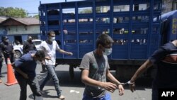 Hombres capturados por supuestos vínculos con pandillas son escoltados por la Policía Nacional Civil durante el estado de emergencia declarado por el gobierno en San Salvador el 31 de marzo de 2022.