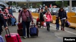 Ukrainians who fled to Mexico amid Russia's invasion of their homeland, walk with their belongings to cross the San Ysidro Land Port of Entry of the U.S.-Mexico border, in Tijuana, Mexico, April 2, 2022