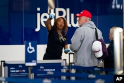 Passengers check in at the terminal at Ronald Reagan Washington National Airport, in Arlington, Va., April 19, 2022, after a federal judge's ruling to strike down a national mask mandate.