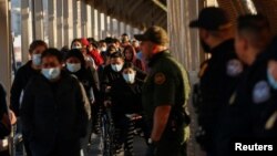 FILE - Migrants expelled from the U.S. and sent back to Mexico under Title 42 walk toward Mexico at the Paso del Norte International border bridge on April 1, 2022. 