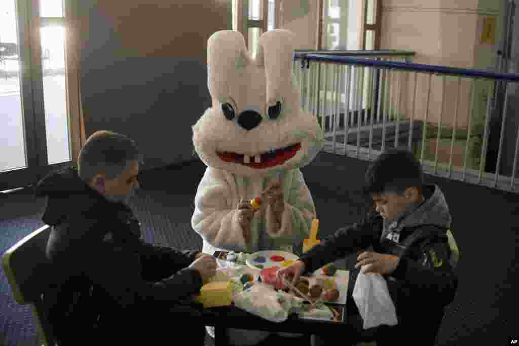 Children who fled the war in Ukraine, paint Easter eggs next to an entertainer dressed in a rabbit costume in a center for refugees in Bucharest, Romania.