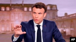 FILE - French President and centrist candidate for reelection Emmanuel Macron gestures during a news broadcast of French TV channel TF1, outside Paris, April 13, 2022.