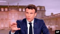 FILE - French President Emmanuel Macron gestures during a news broadcast of French TV channel TF1, outside Paris, April 13, 2022. 