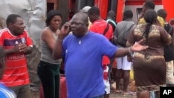 Les rescapés se tiennent à côté des wagons déraillés après l’accident d’un train a l’entrée de la gare Eseka, au Cameroun, 21 octobre 2016.