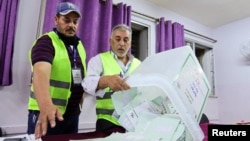 Electoral staff members empty a ballot box at a polling station after voting ended during parliamentary elections in Amman, Jordan, Sept. 10, 2024.