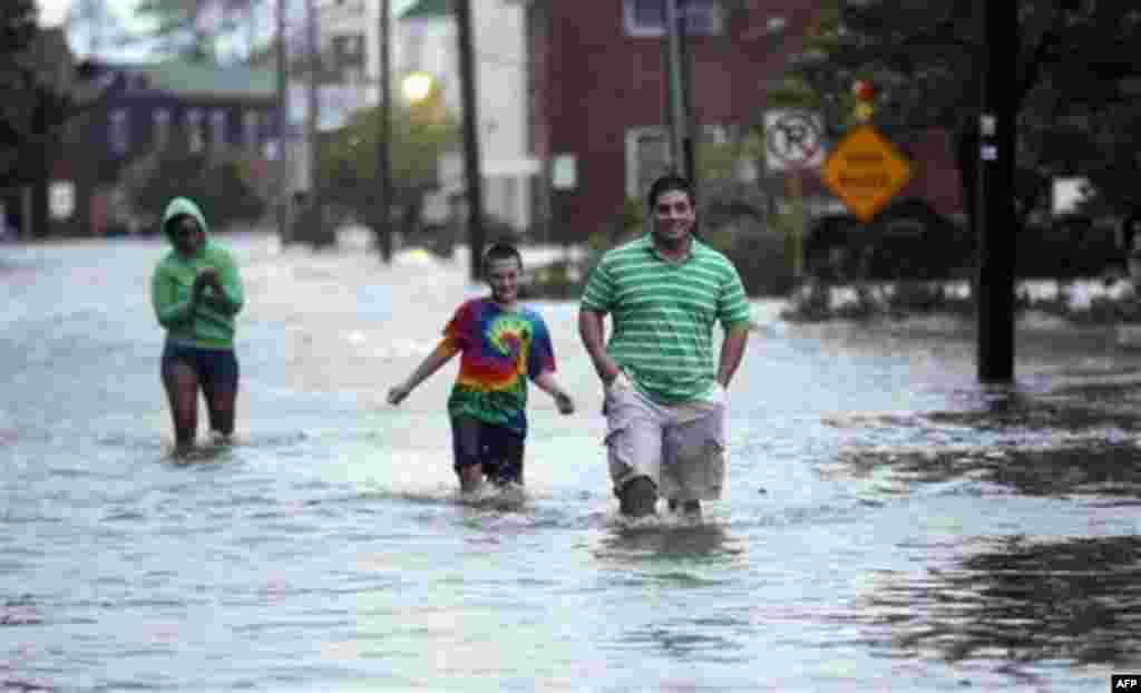 People wade through a street flooded by Hurricane Irene Saturday, Aug. 27, 2011 in Manteo, N.C. Hurricane Irene knocked out power and piers in North Carolina, clobbered Virginia with wind and churned up the coast Saturday to confront cities more accustom