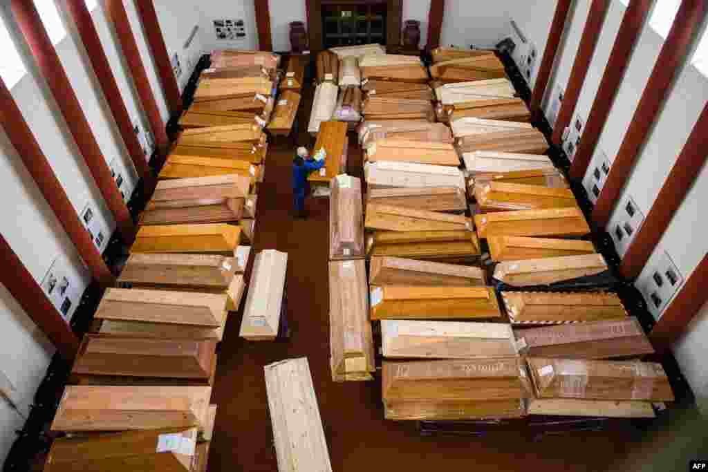 An employee stores coffins in the mourning hall of the crematorium in Meissen, Germany. Most of the deceased, who will be cremated here, have died of or with COVID-19.