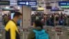 Pemudik yang memakai masker berbaris di loket imigrasi di stasiun Lok Ma Chau setelah dibukanya kembali perbatasan lintas negara dengan China daratan, di Hong Kong, Minggu, 8 Januari 2023. (Foto: AP)