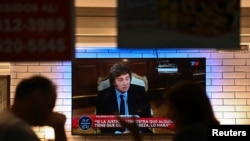 People sit in a restaurant as Argentina's President Javier Milei is seen on television during an interview, in Buenos Aires, Argentina, Feb. 17, 2025. 