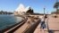 FILE - A lone tourist poses for a photo in Circular Quay in Sydney on March 20, 2020, after Australia moved to seal off its borders to help stop the spread of COVID-19.