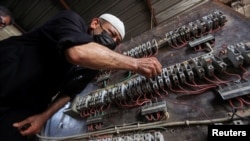 FILE - A man works on an electrical generator board during power outages in Basra, Iraq, Aug. 21, 2021. 