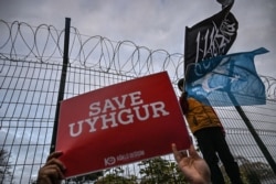 A supporters of China's Muslim Uighur minority holds a placard reading "Save Uighur" as a boy waves the flag of East Turkestan and an Islamic black flag on December 13, 2019 during a demostration in front of China Consulate in Istanbul.