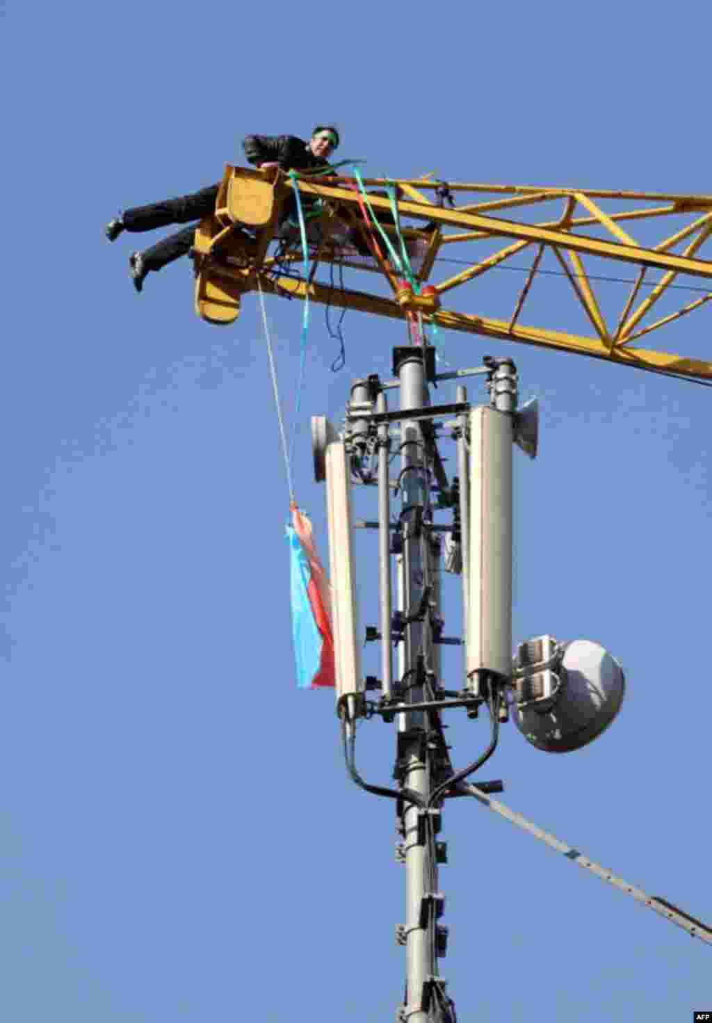 A man wearing a green headband hangs from the top of a crane before attempting suicide in central Tehran