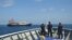 FILE - In this April 27, 2021, photo provided by the Philippine Coast Guard, its personnel patrol beside ships said to be Chinese militia vessels at Sabina Shoal in the South China Sea.