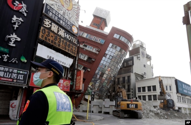 A police officer stands guard near a partially collapsed building a day after a powerful earthquake struck in Hualien City, eastern Taiwan, Thursday, April 4, 2024. (AP Photo/Chiang Ying-ying)