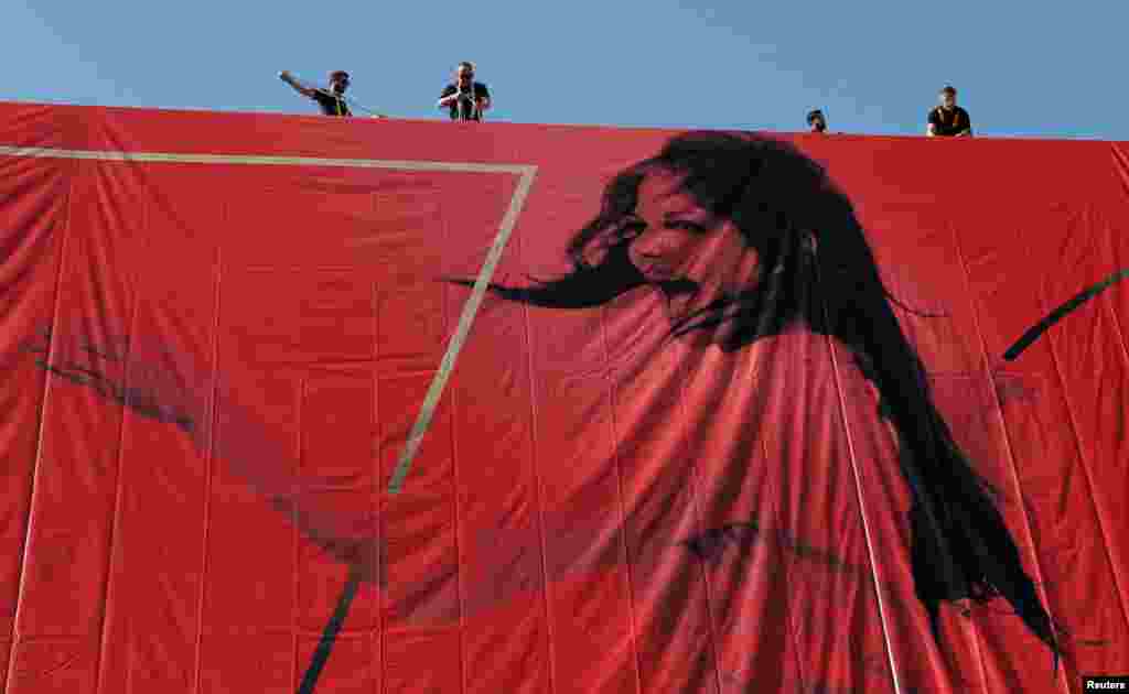Workers set up a giant canvas of the official poster of the 70th Cannes Film Festival, featuring actress Claudia Cardinale, on the facade of the Palais des Festivals in Cannes, southeastern France, May 15, 2017.
