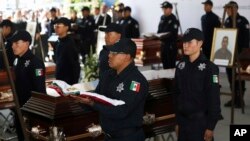 ARCHIVO - La policía vigila junto a los ataúdes que contienen los restos de 13 policías mexicanos asesinados en una aparente emboscada de un cartel, durante un servicio conmemorativo en Morelia, México, el 15 de octubre de 2019.