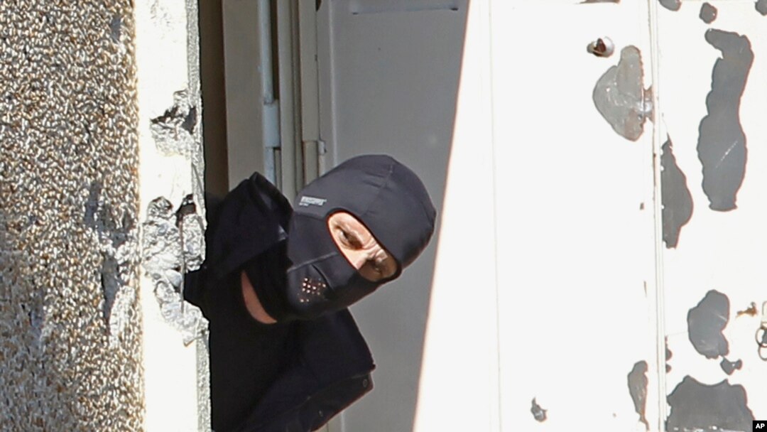 FILE - A masked policeman searches for clues at terrorist Mohamed Merah's apartment building in Toulouse, southern France. 