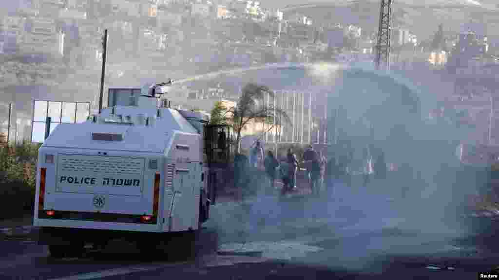 An Israeli police truck sprays water during during clashes between Arab youths and Israeli police at the entrance to the town of Kfar Kanna, in northern Israel, Nov. 8, 2014.