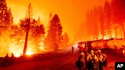 The Caldor Fire burns along both sides of Highway 50 as firefighters work to stop its eastward spread in Eldorado National Forest, Calif., on Aug. 26, 2021.