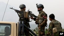 FILE - Afghan military soldiers stand stand alert at the entrance gate of the new parliament building after a rocket attack in Kabul, Afghanistan.