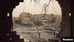 People walk down a street are pictured through a hole in a building in Deir al-Zor, Syria, April 4, 2013. 