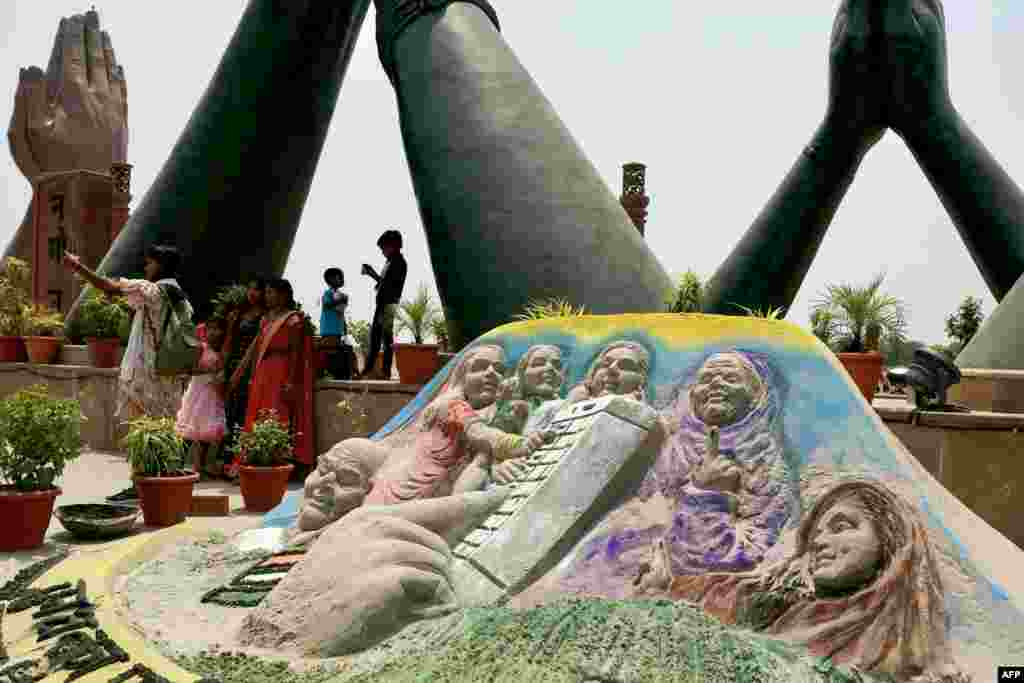 مردم در حال گرفتن عکس در کنار یک اثر هنری ساخته شده از ریگ در شهر ورانسی؛ این اثر به هدف افزایش اگاهی عامه برای دادن رای در انتخابات سراسری هند طراحی شده است. &nbsp;