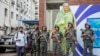 FILE - Military personnel stand guard in front of a large cutout portrait of Prime Minister Sheikh Hasina in Dhaka, Bangladesh, July 30, 2024. Interim leader Muhammad Yunus said, Nov. 17, 2024, that his administration will seek the extradition of ousted prime minister from India.