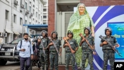 Military personnel stand guard in front of a large cutout portrait of Prime Minister Sheikh Hasina during the national mourning day, declared by the Bangladesh government to remember victims of the recent countrywide deadly clashes, in Dhaka, Bangladesh, July 30, 2024.