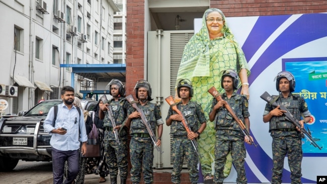 Military personnel stand guard in front of a large cutout portrait of Prime Minister Sheikh Hasina during the national mourning day, declared by the Bangladesh government to remember victims of the recent countrywide deadly clashes, in Dhaka, Bangladesh, July 30, 2024.