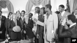 FILE - Presiden Jimmy Carter memegang bola basket yang diberikan oleh anggota tim basket Universitas Louisville di Gedung Putih, Washington, 3 April 1980. Para Juara NCAA berkunjung ke Gedung Putih setelah menghadiri jamuan makan siang di Capitol Hill. (Mark Wilson, Arsip/AP)