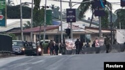 FILE — Hooded men in military fatigues stand on a street after unidentified gunmen attacked military barracks and attempted to break into an armory in Freetown, Sierra Leone, Nov. 26, 2023.