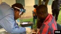 A father holds his 5-year-old daughter as she gets the Ebola trial vaccine in Kasese district Uganda, June 16, 2019. (H. Athumani for VOA)